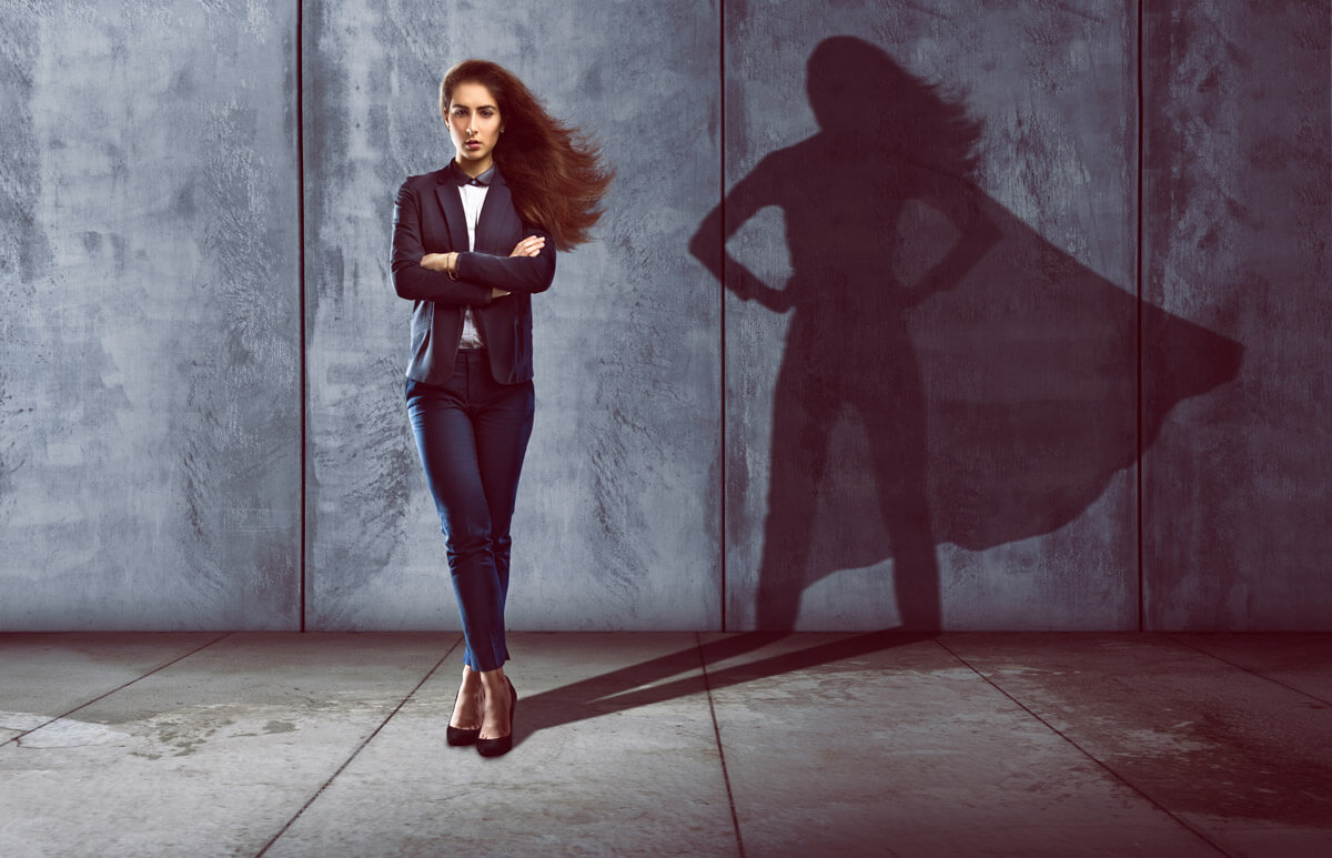 Business woman standing with super hero silhouette against background