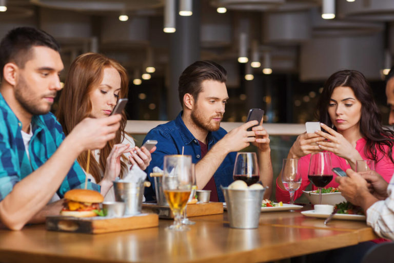 People eating a meal all looking at their phones instead of talking